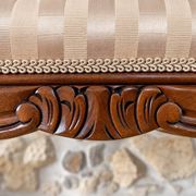 Two-seater bench in carved wood, with curved armrests.