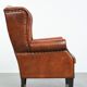 Large sheepskin wingback chair with black piping and decorative nails