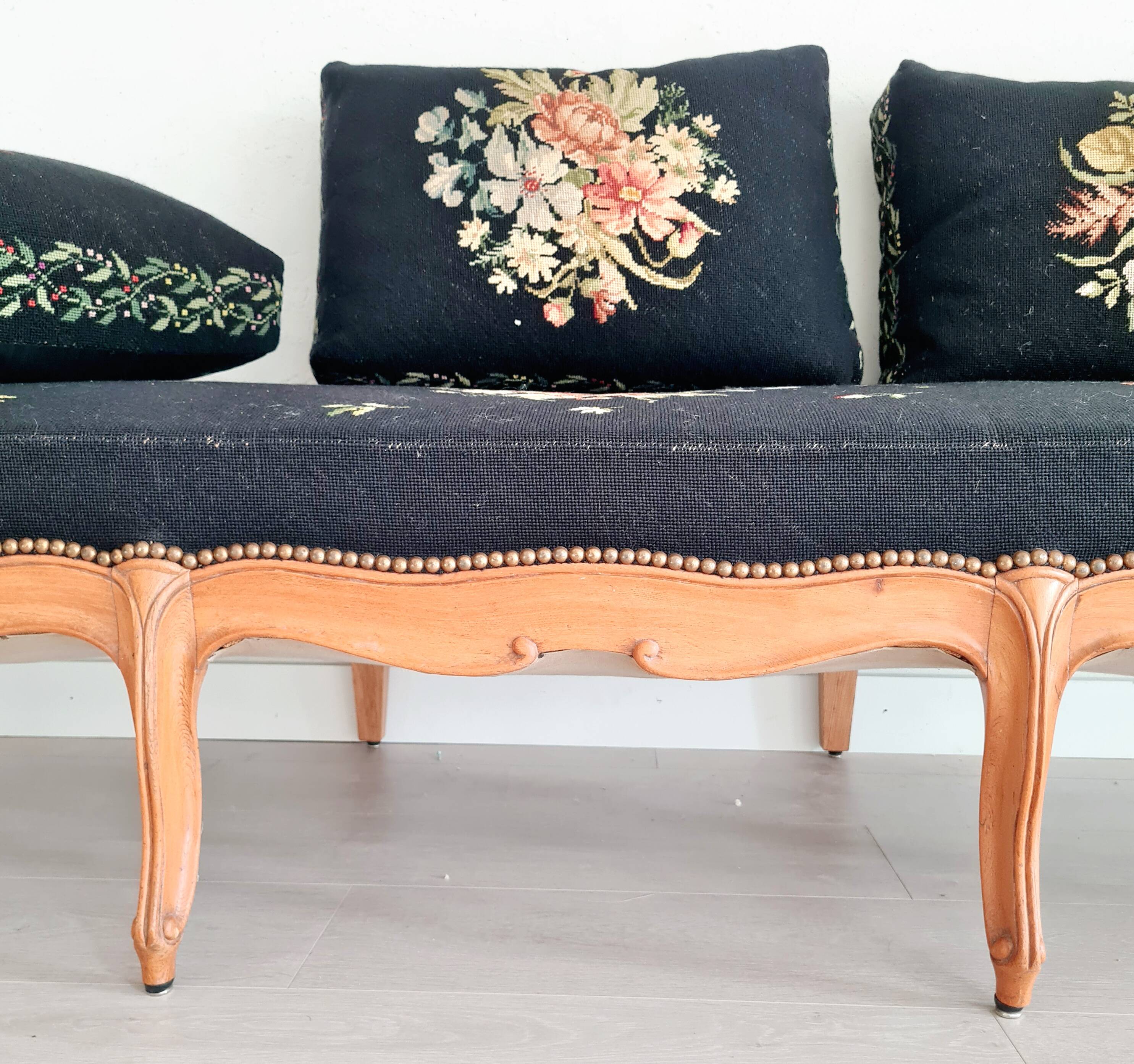Old bench upholstered in black canvas flowers