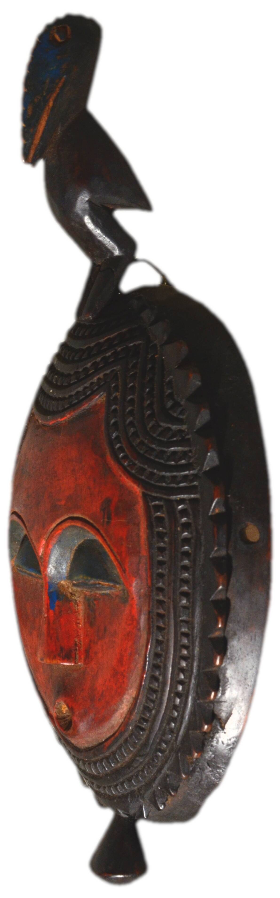 African wooden mask, face topped with a bird.