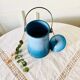 Old vintage milk jug in degraded blue enameled sheet metal