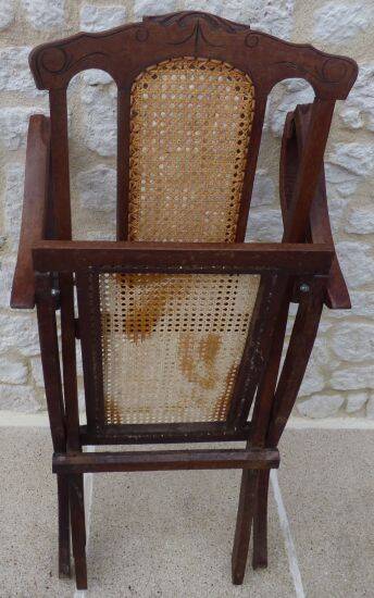 Antique folding chair with caned seat and backrest made of wood.