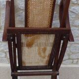 Antique folding chair with caned seat and backrest made of wood.