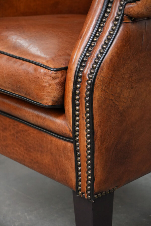 Fauteuil à oreilles en cuir de mouton avec passepoil noir en bon état
