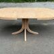 Renovated oval Scandinavian extendable dining table in wood with a central leg.