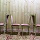 Louis XVI dining room table set with painted wood, gold accents, and pink velvet.