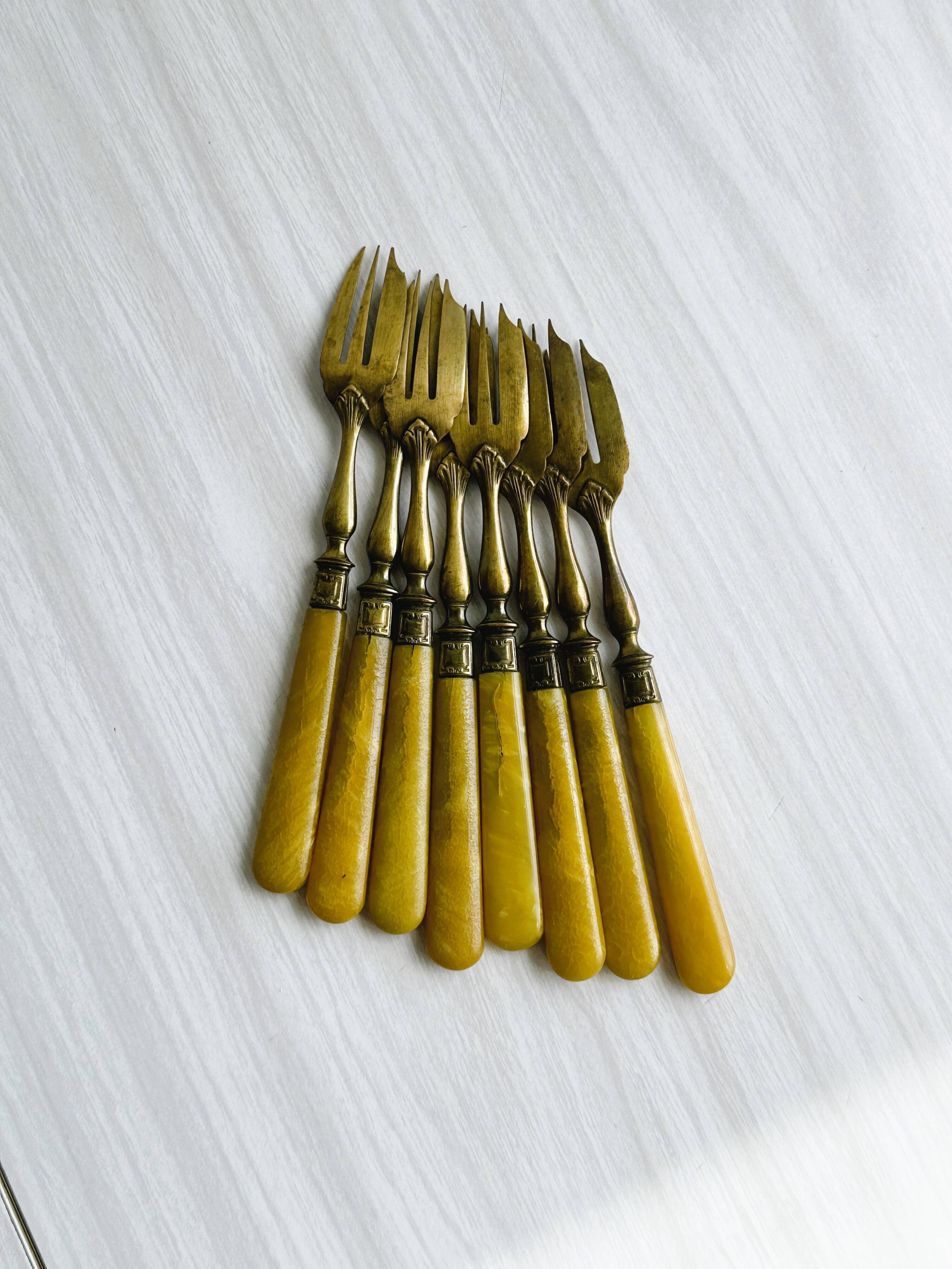 8 fourchettes à dessert vintage en métal doré et  manches en bakélite jaune.