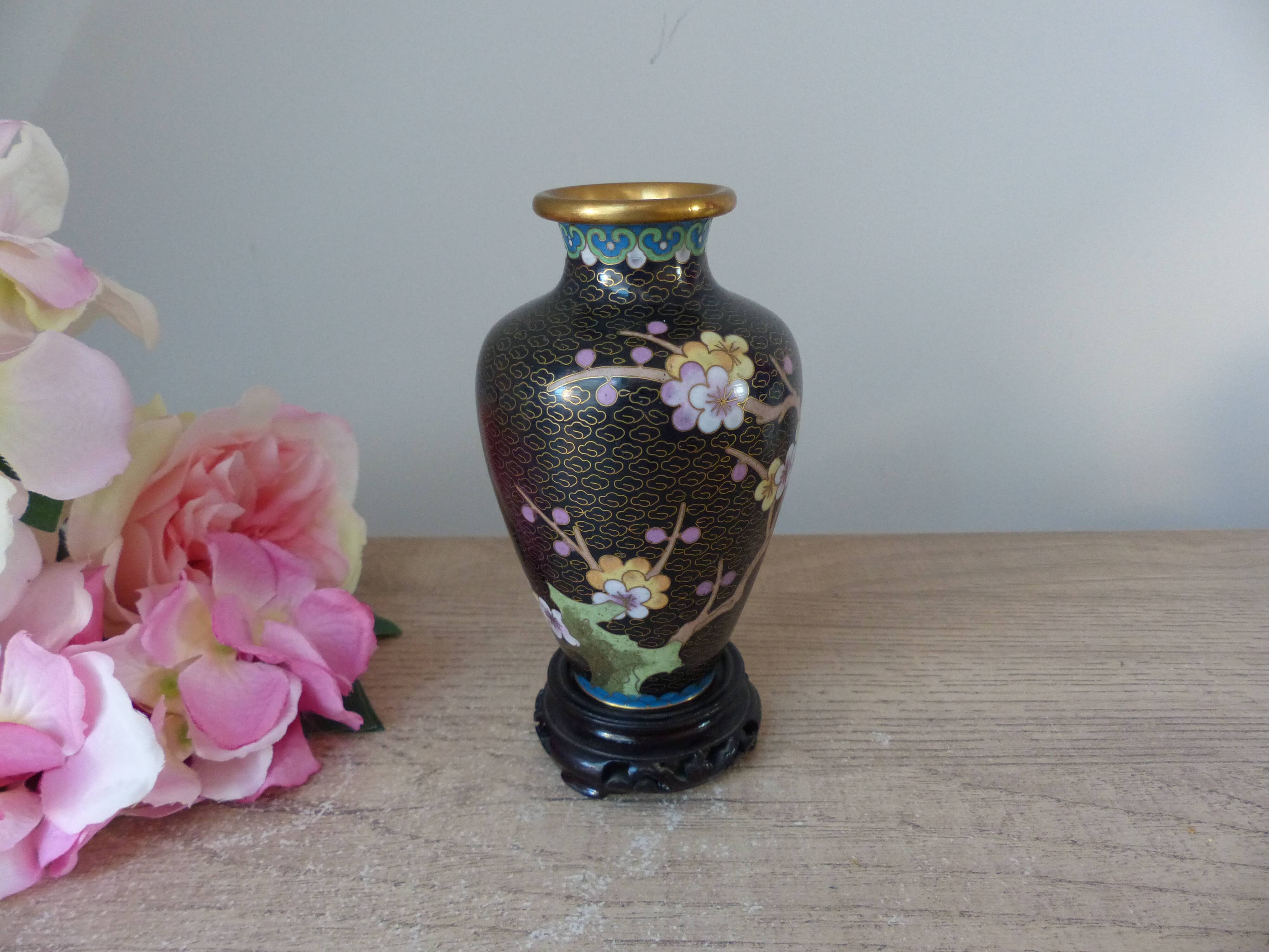 Small black cloisonné vase decorated with yellow and pink cherry blossoms, vase on wooden base