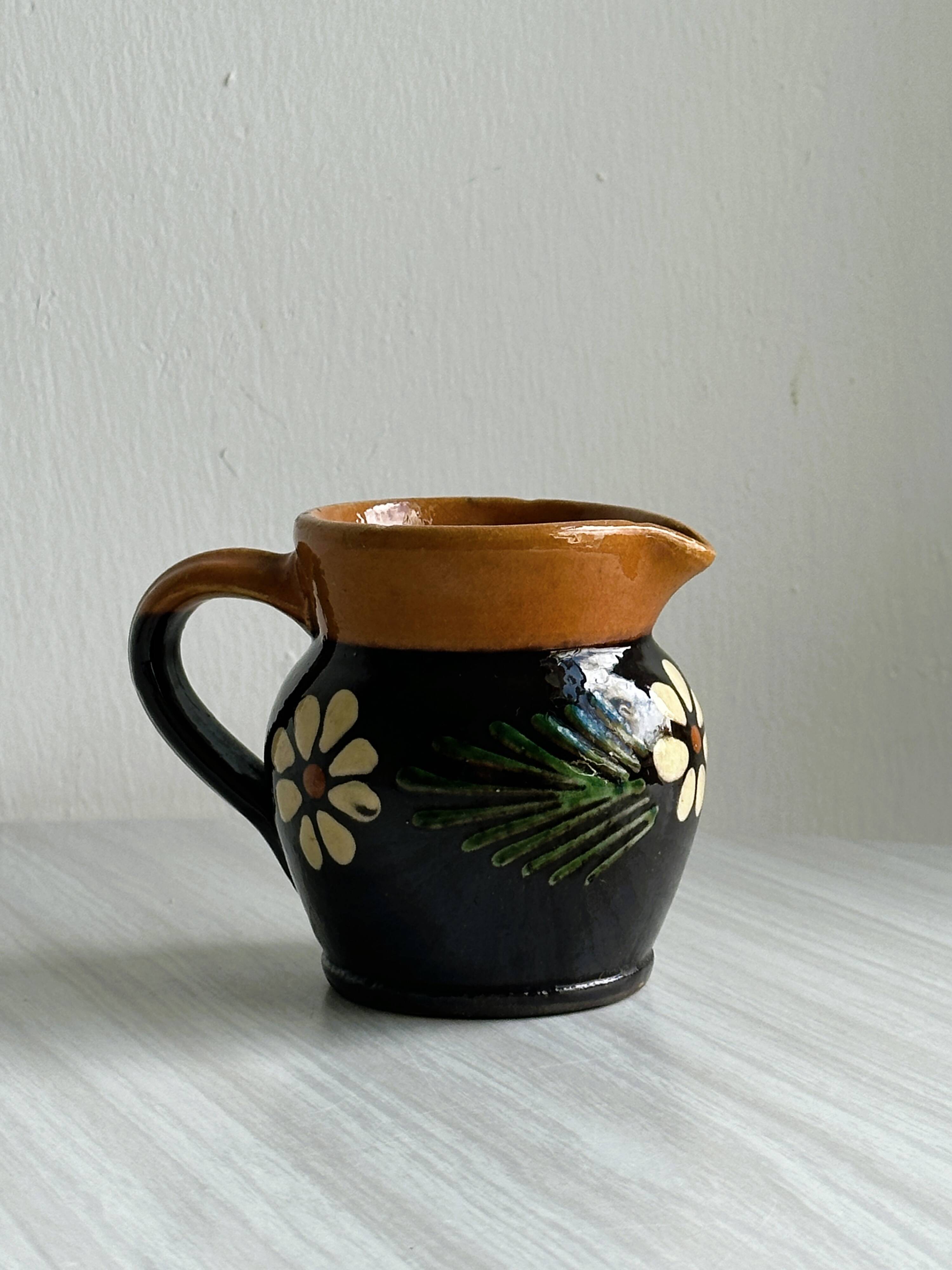 Petit pichet Alsacien en céramique noire et marron, décoré de motifs floraux peints à la main.