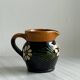Petit pichet Alsacien en céramique noire et marron, décoré de motifs floraux peints à la main.