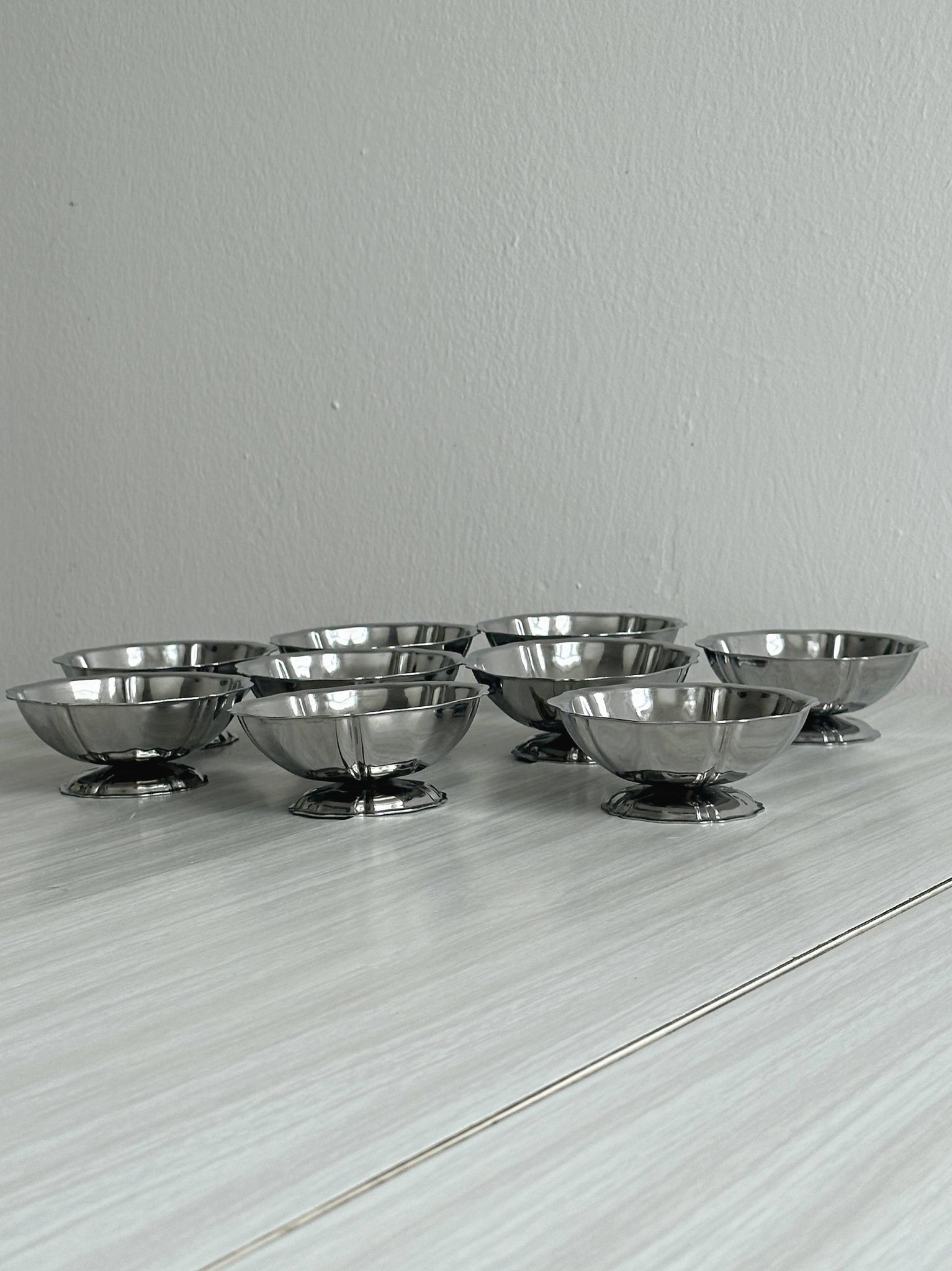 Set of 9 low bowls in shiny stainless steel.