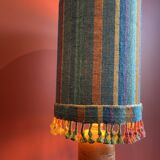 "Stoneware Bottle Lamp" with a multicoloured blue lampshade handwoven in India.