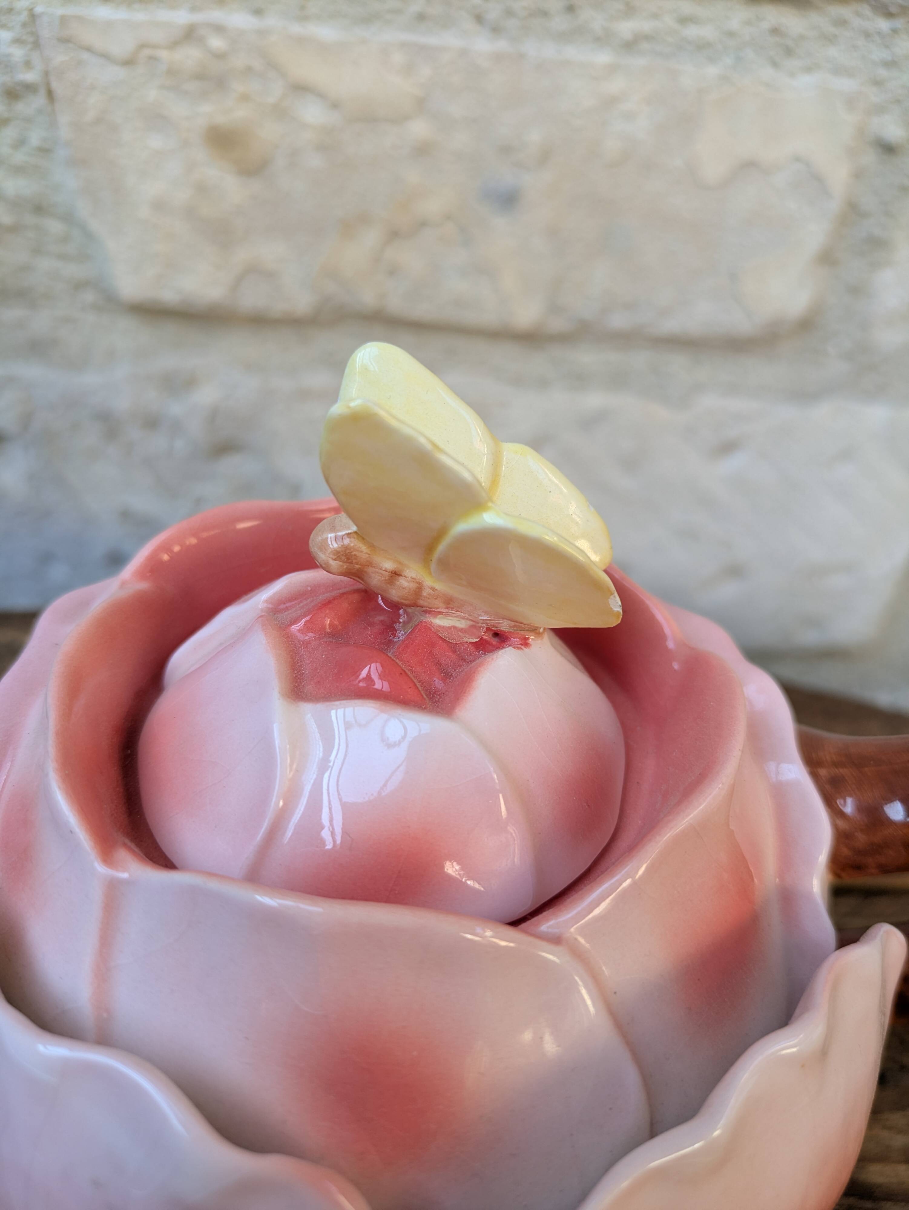 Ceramic teapot in the shape of a rose with a butterfly and raised petals.