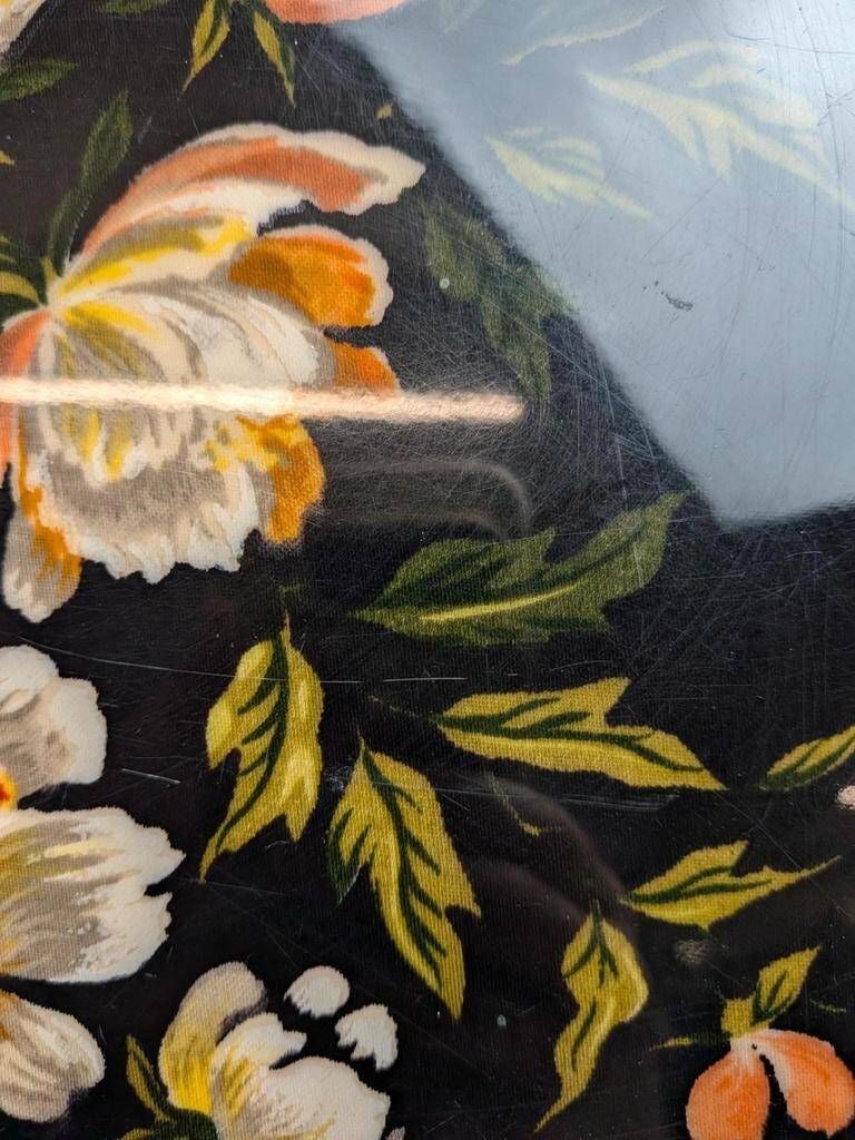 Large vintage 1960s platter with floral decoration on a black background and golden handles.