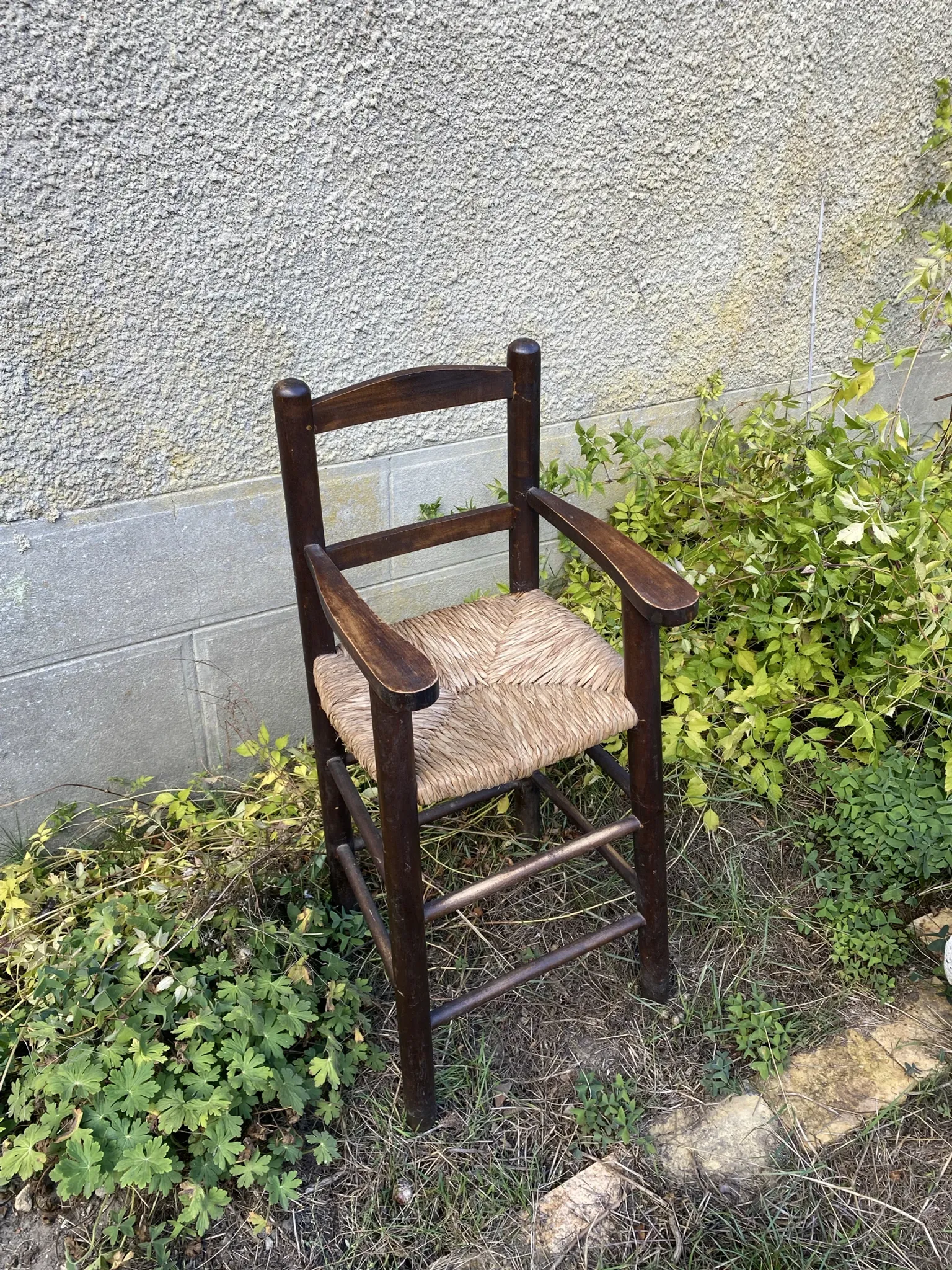 Vintage wooden children's high chair with straw.