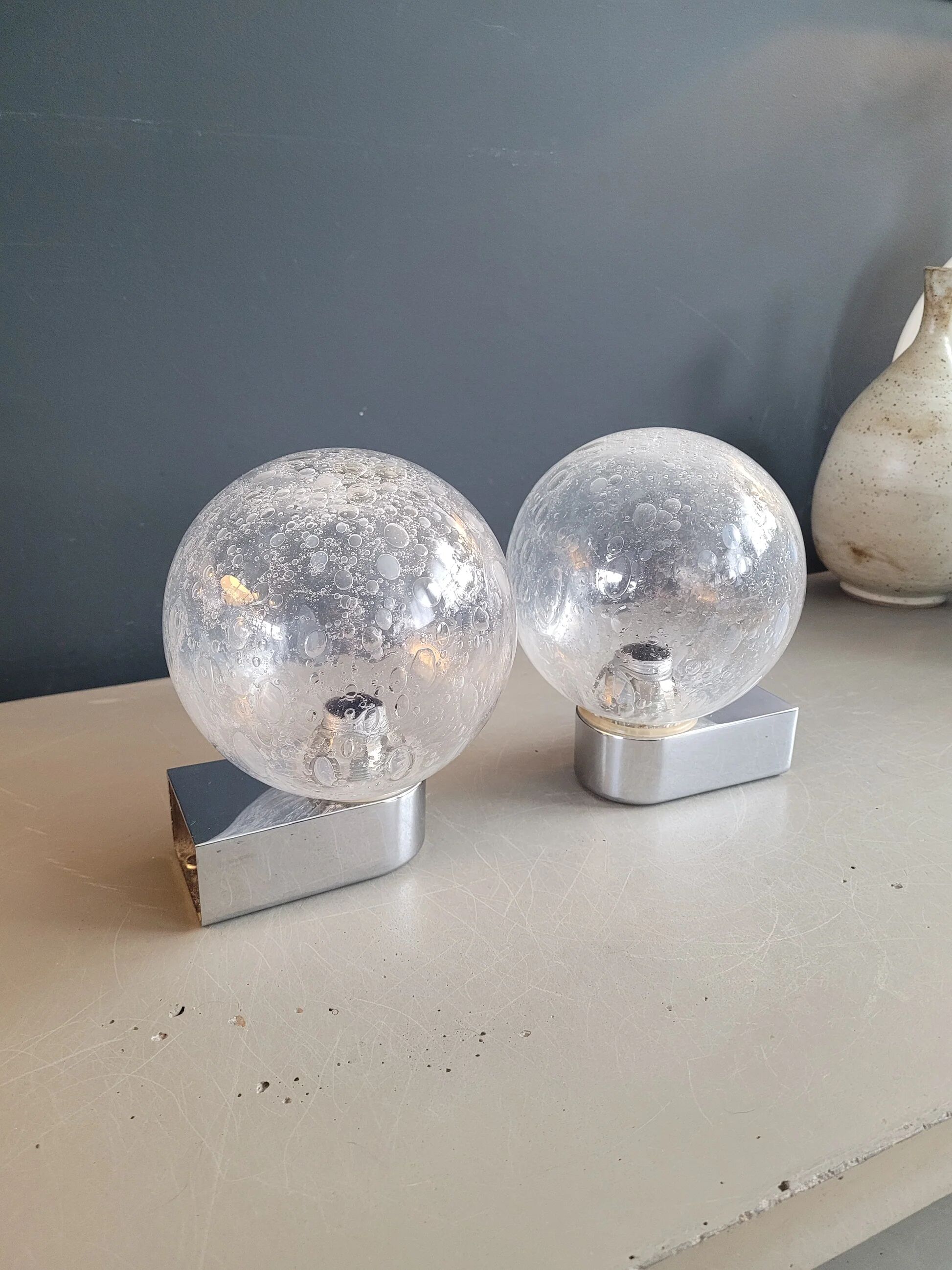 Pair of vintage wall lights in chrome metal with bubbled glass globes.