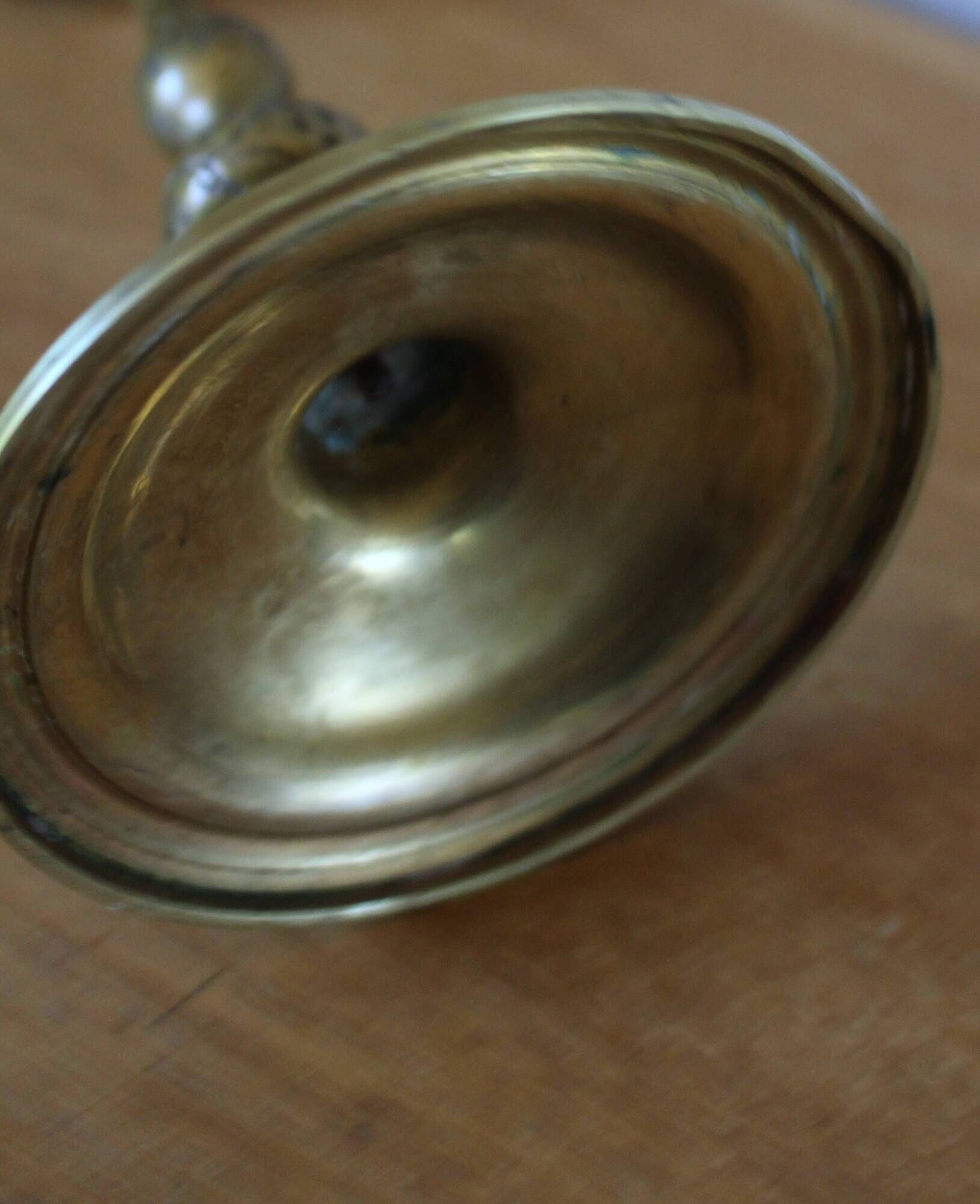 Brass candle holder with flowers and round shape.