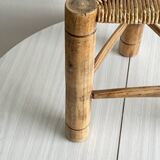 Antique tripod stool in light wood with a woven straw seat.