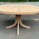 Renovated oval Scandinavian extendable dining table in wood with a central leg.