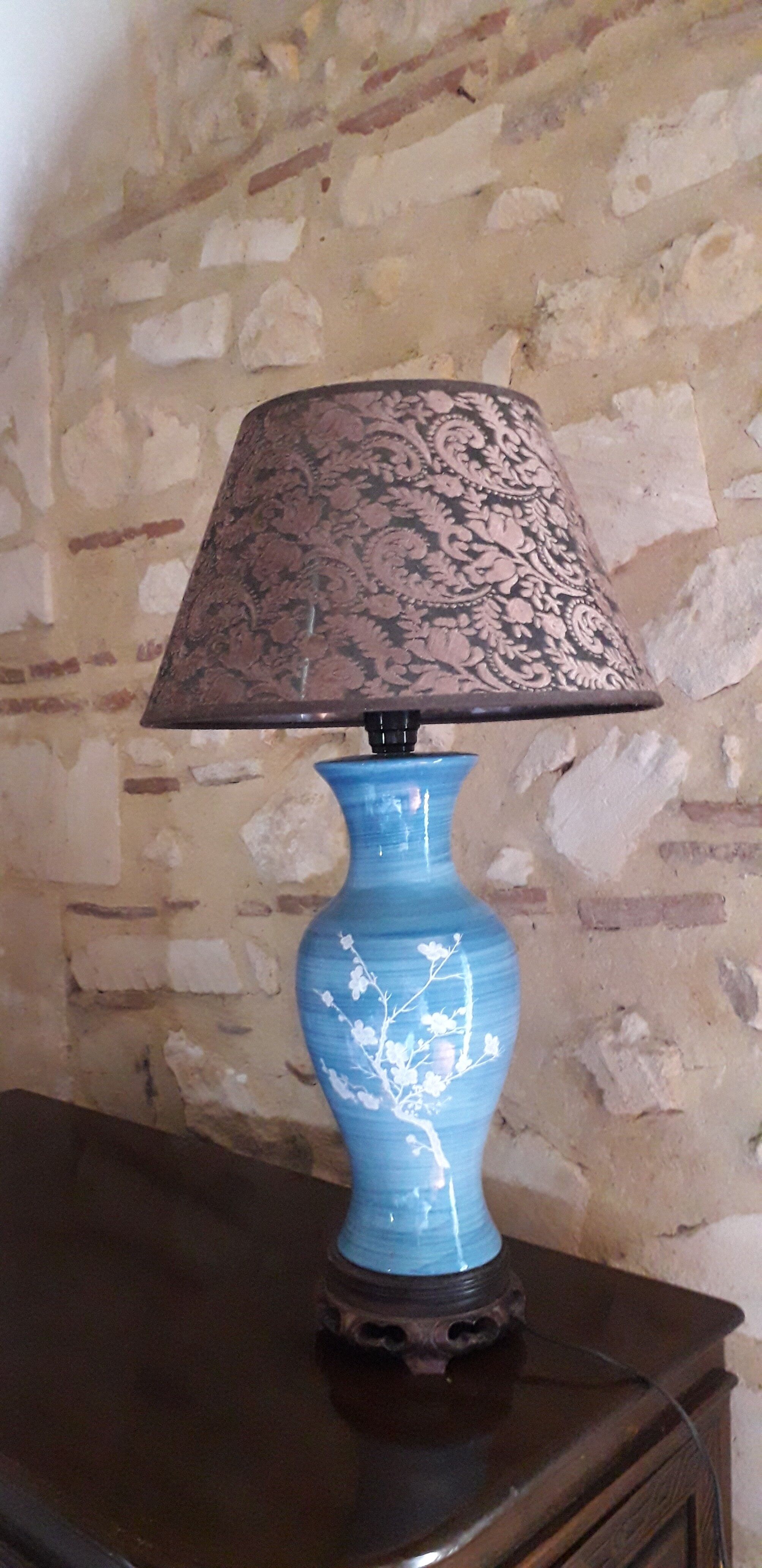 Large blue porcelain lamp with white flowers (cherry blossoms) on wooden stand.