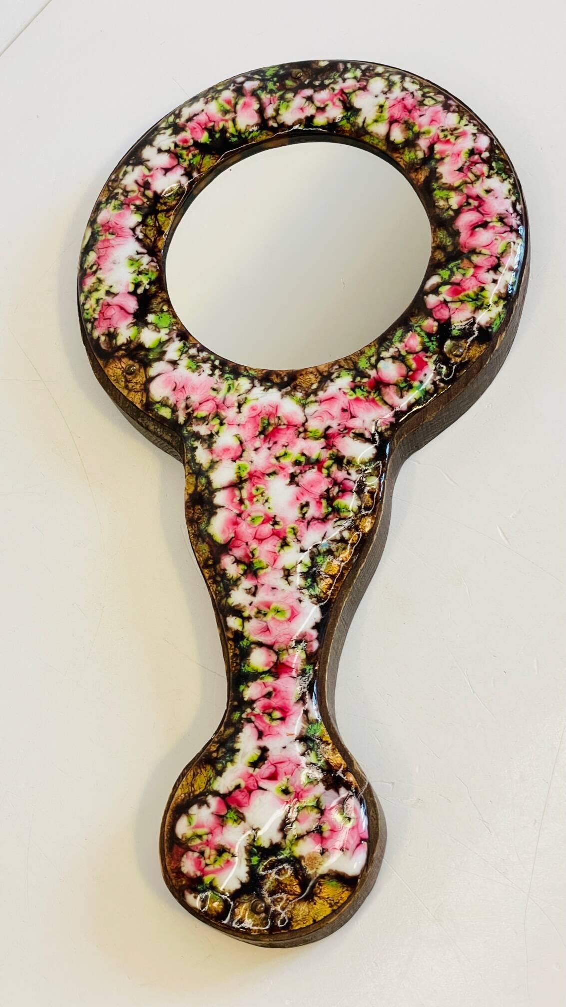 Vintage enameled metal hand mirror on wood