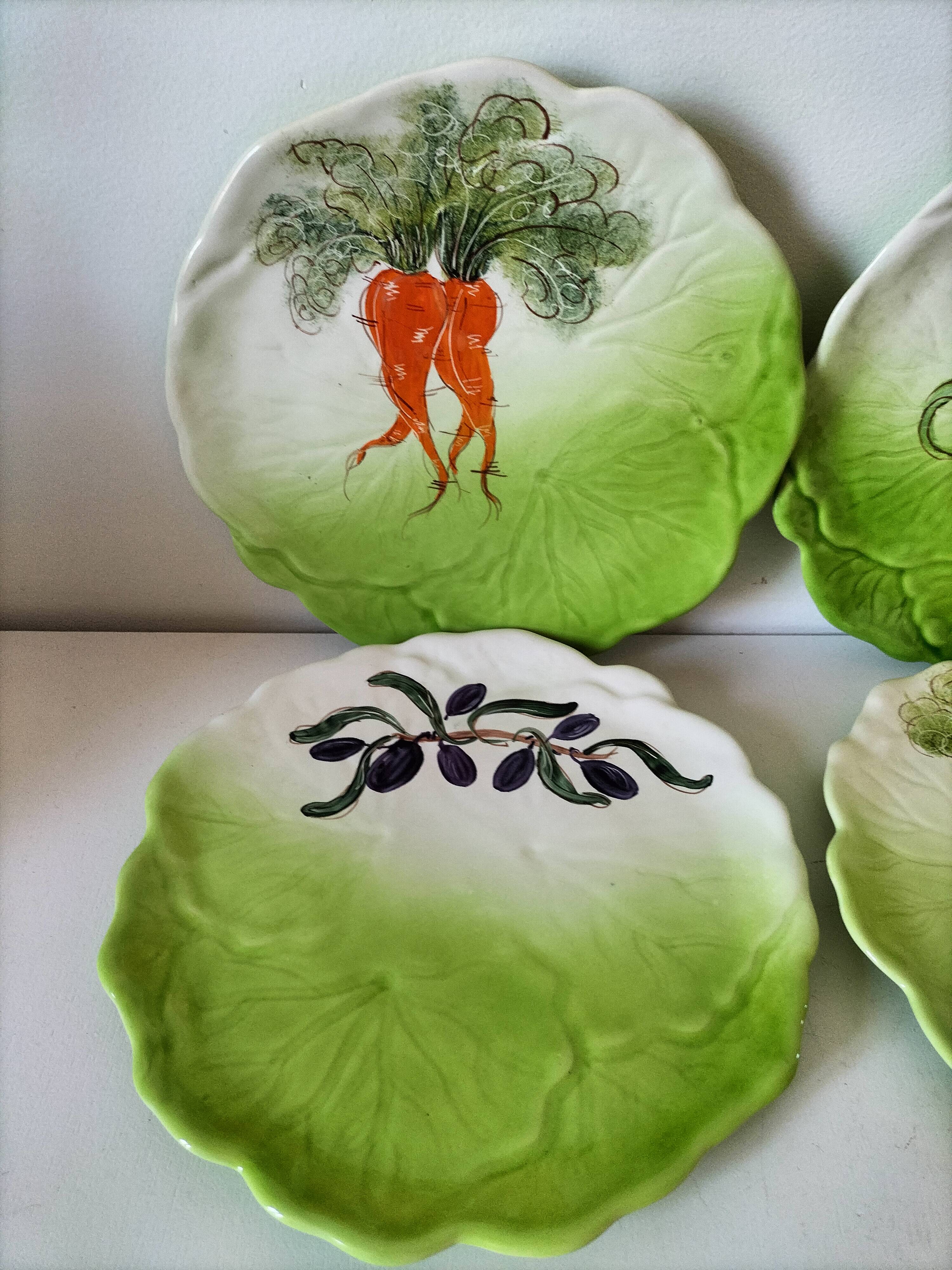 4 hand-decorated earthenware plates with vegetable and green leaf designs.