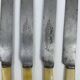 Set of 4 dessert knives with rounded tips and smooth ivory resin handles.