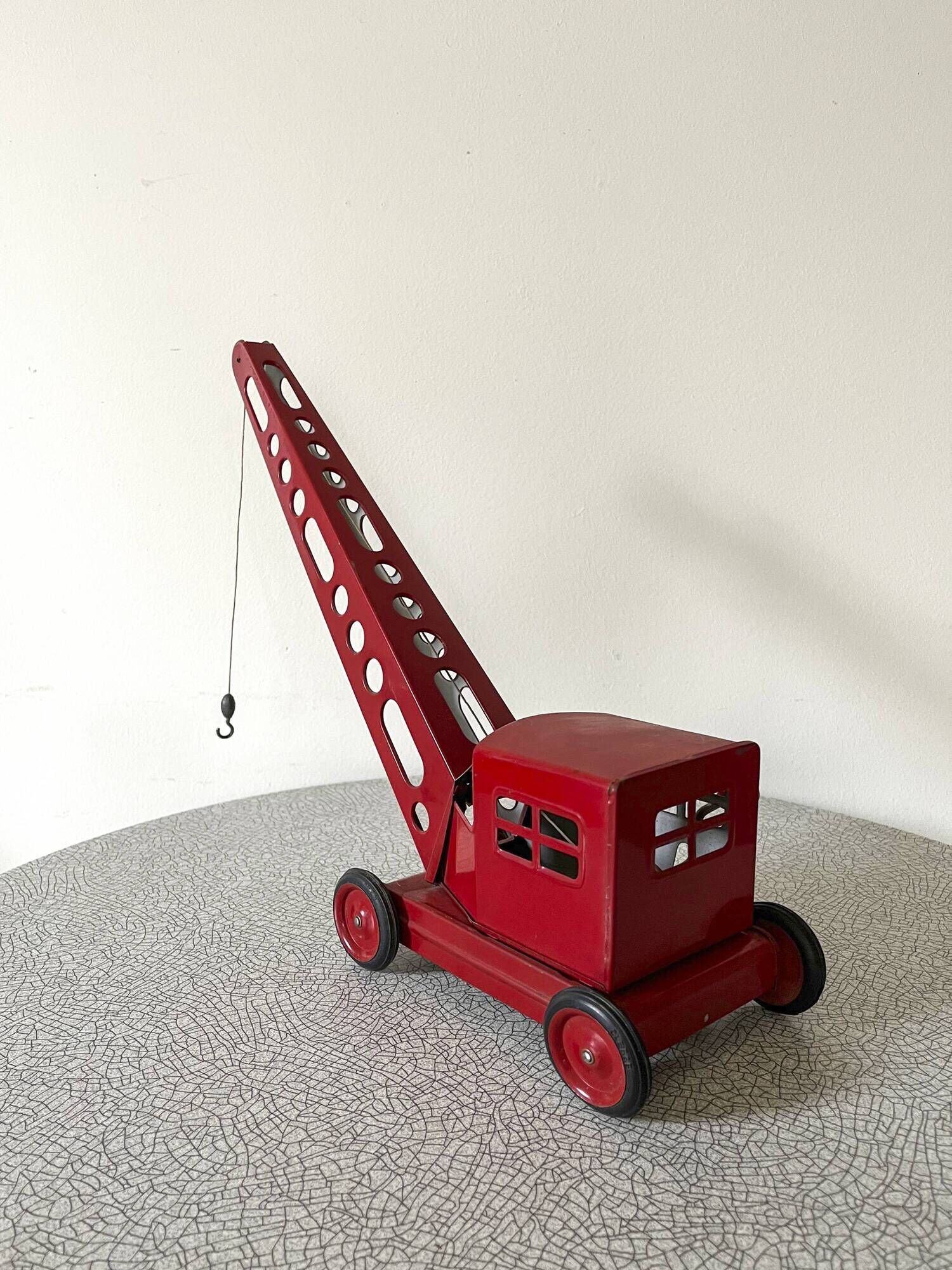 Grue de chantier rouge en tôle datant des années 60 avec mécanisme manuel