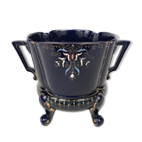 Large earthenware pot cover with enamelled decoration on a blue oven background