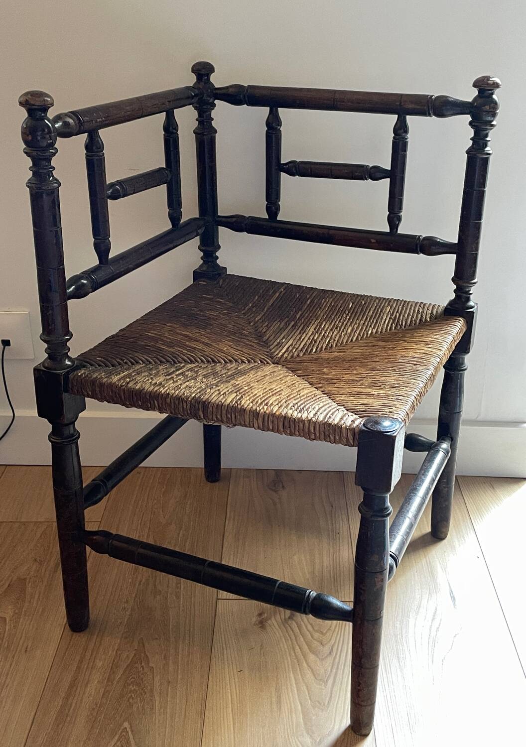 Corner chair made of turned wood with a straw seat.