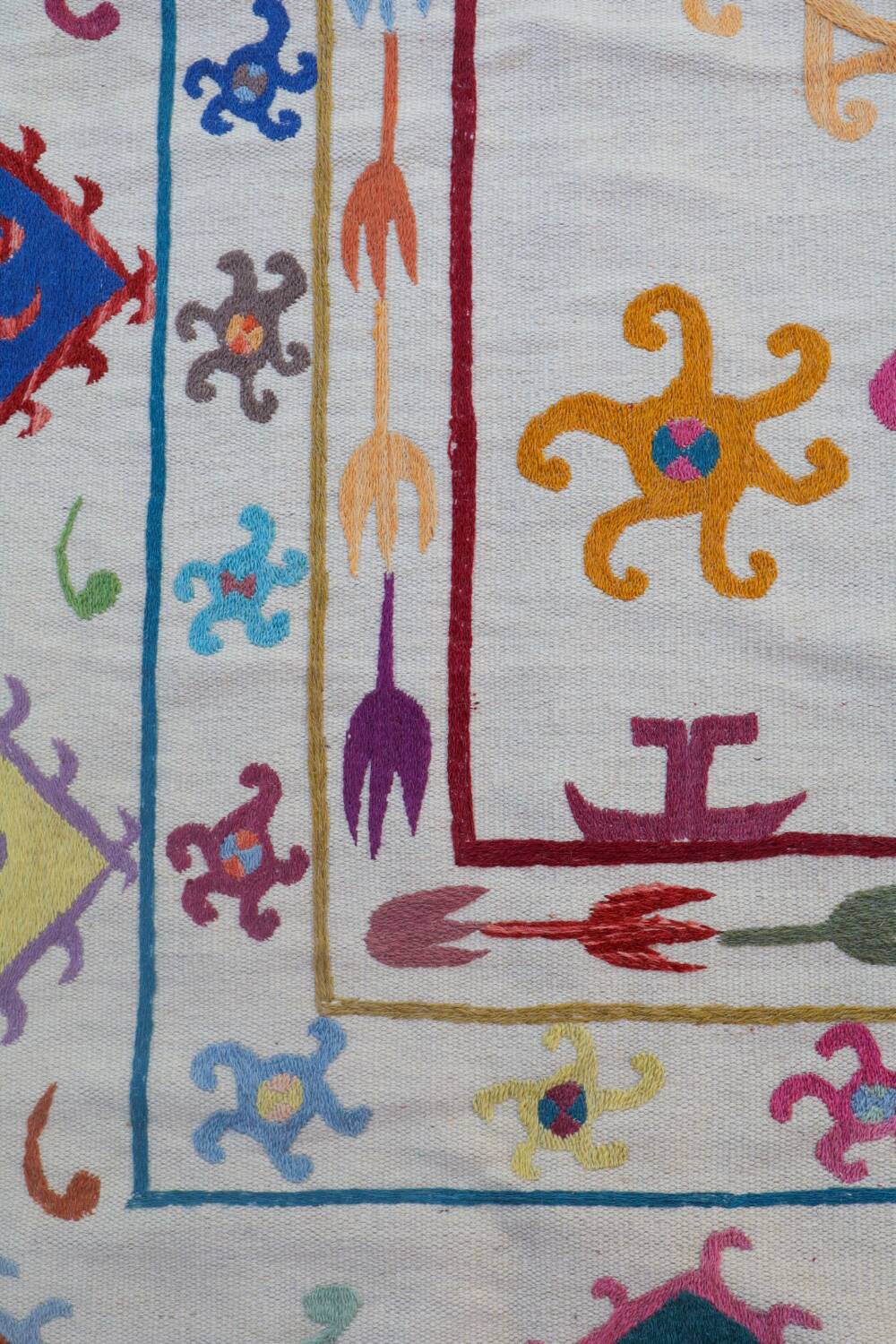 White suzani kilim rug with multi-colored embroidered patterns