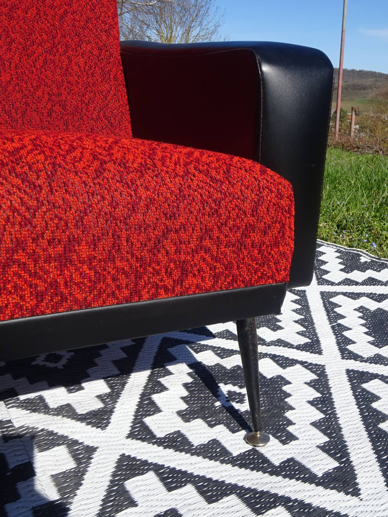 Pair of vintage armchairs in black faux leather and red fabric.
