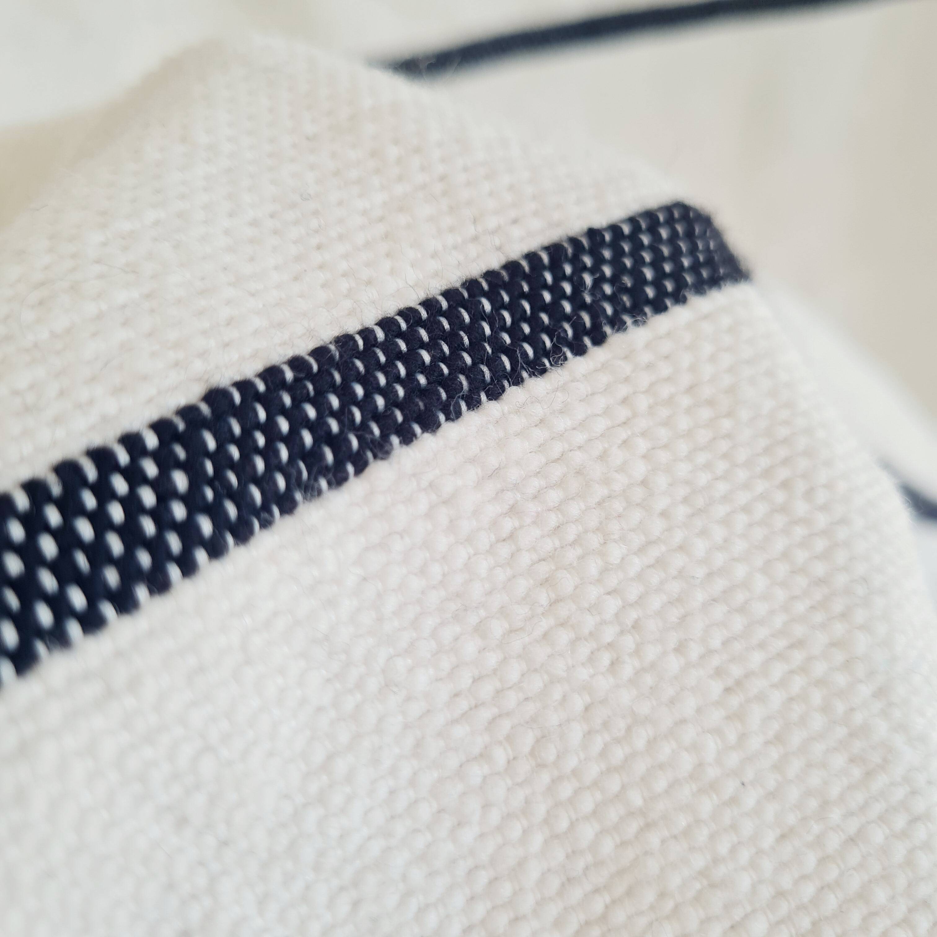 Handwoven throw with black stripes and pom-poms