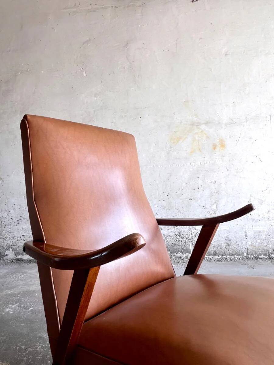 Vintage armchair from the 1950s in cognac leather and dark wood — modernist lounge chair.