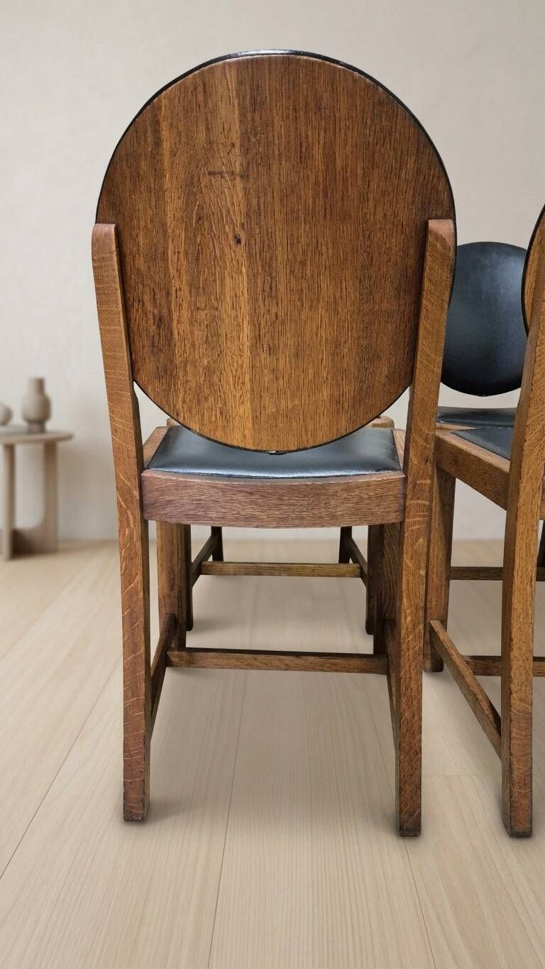 Set of four vintage wooden dining chairs with black leather upholstery