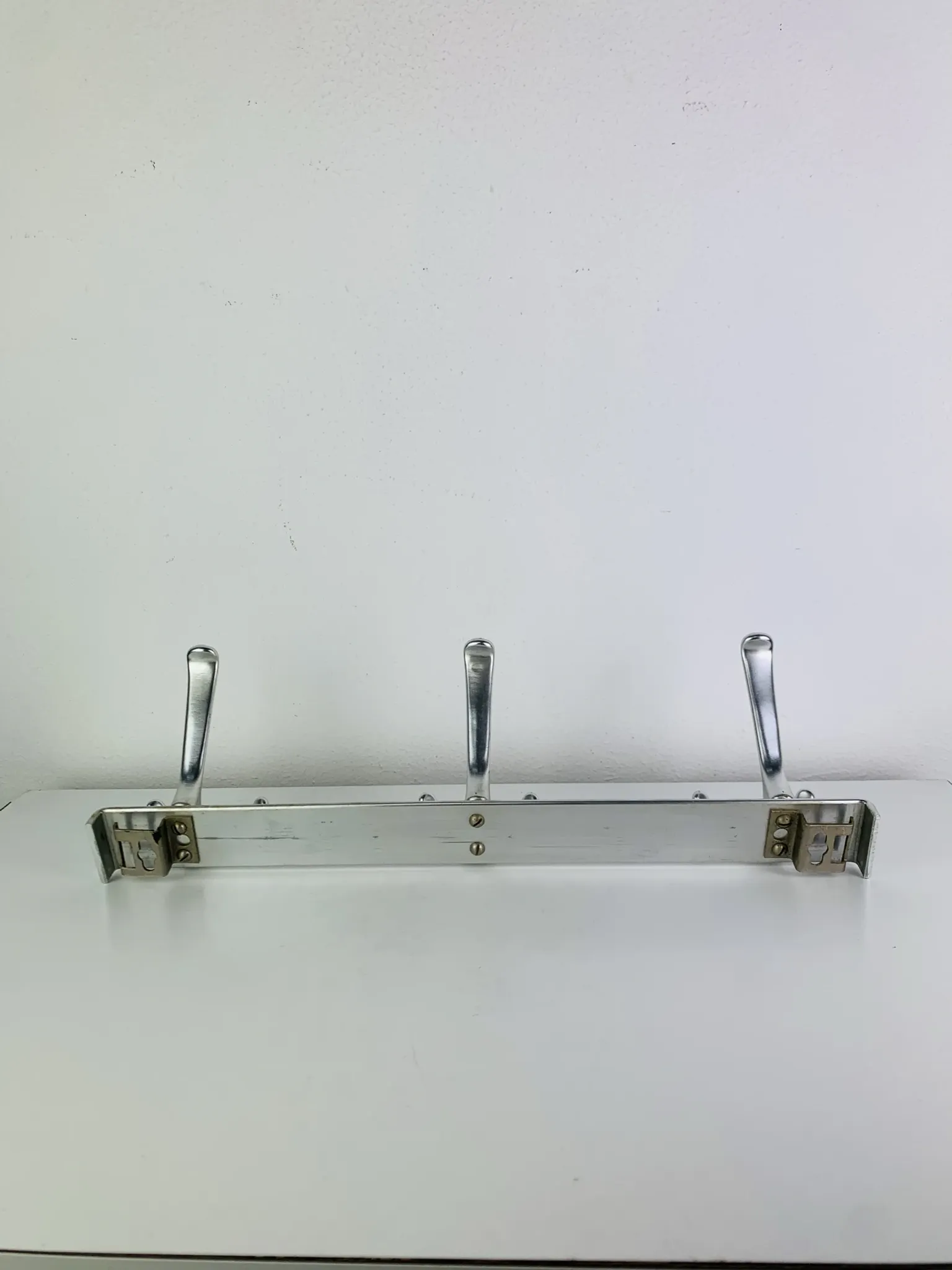 Wall-mounted coat rack, strip of 3 aluminium hooks from the 1960s.