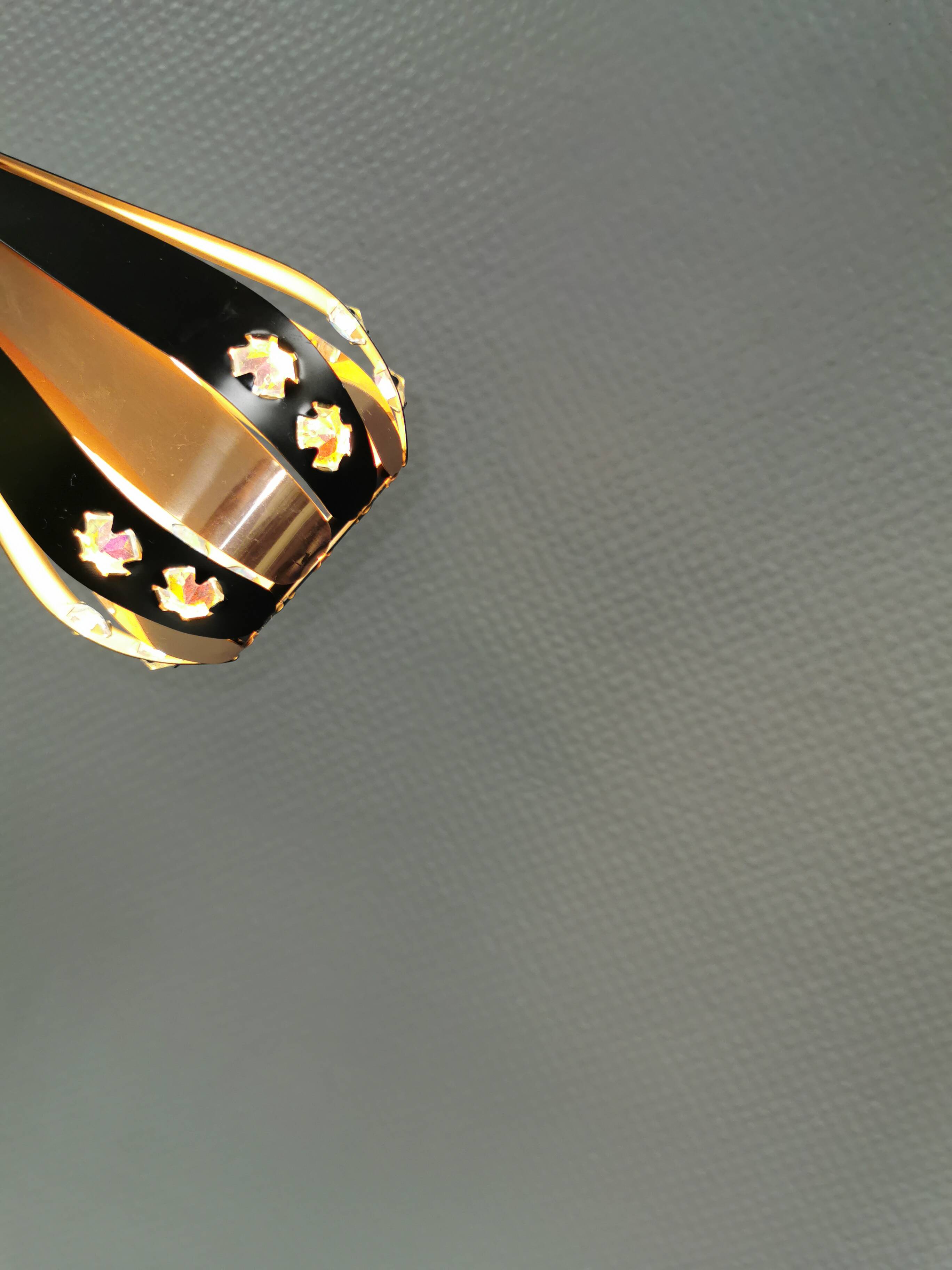 A teardrop-shaped pendant lamp made of copper, black metal, and prisms.