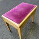 Adjustable piano stool in light beech and purple velvet.