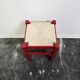Tabouret en bois rouge avec assise en paille tressée.