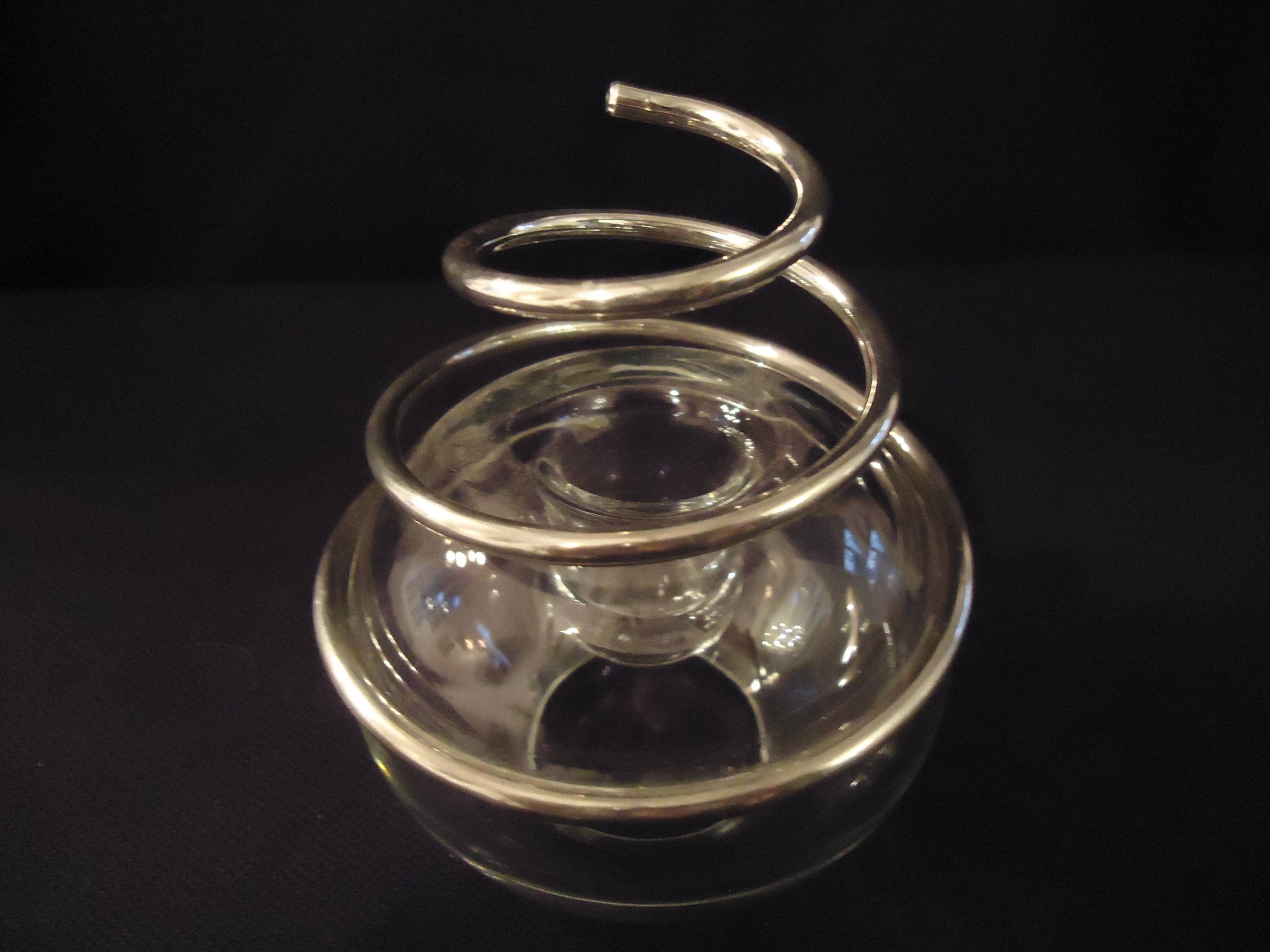 Round glass candle holder with silver-plated metal spiral.