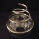 Round glass candle holder with silver-plated metal spiral.