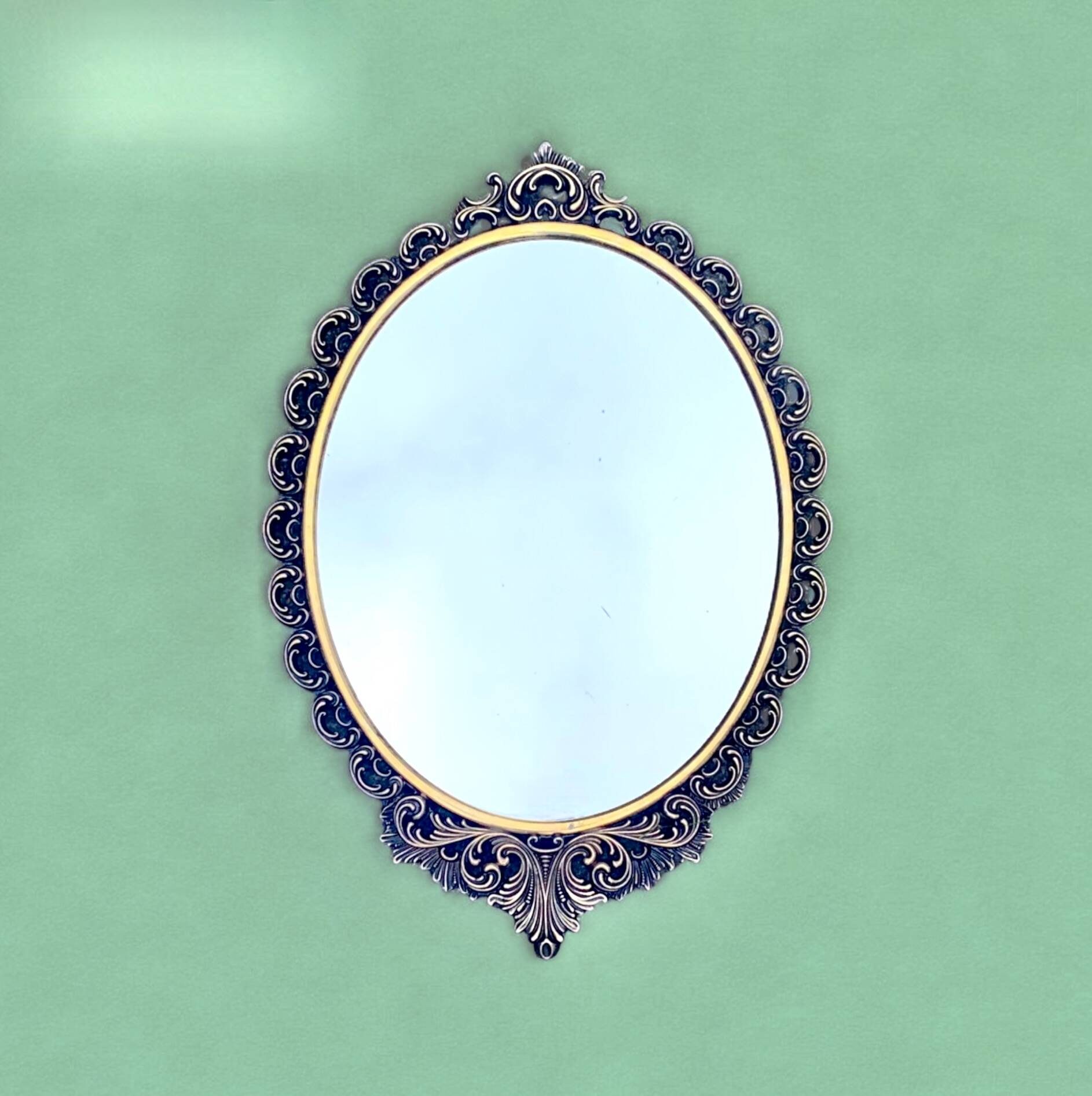 Old oval wall mirror in gilded brass