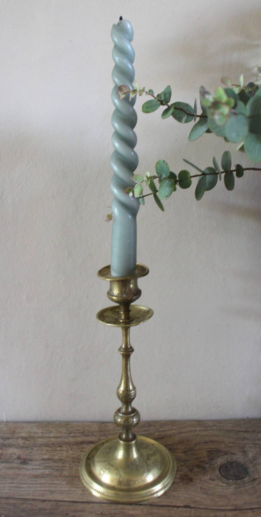 Brass candle holder with flowers and round shape.