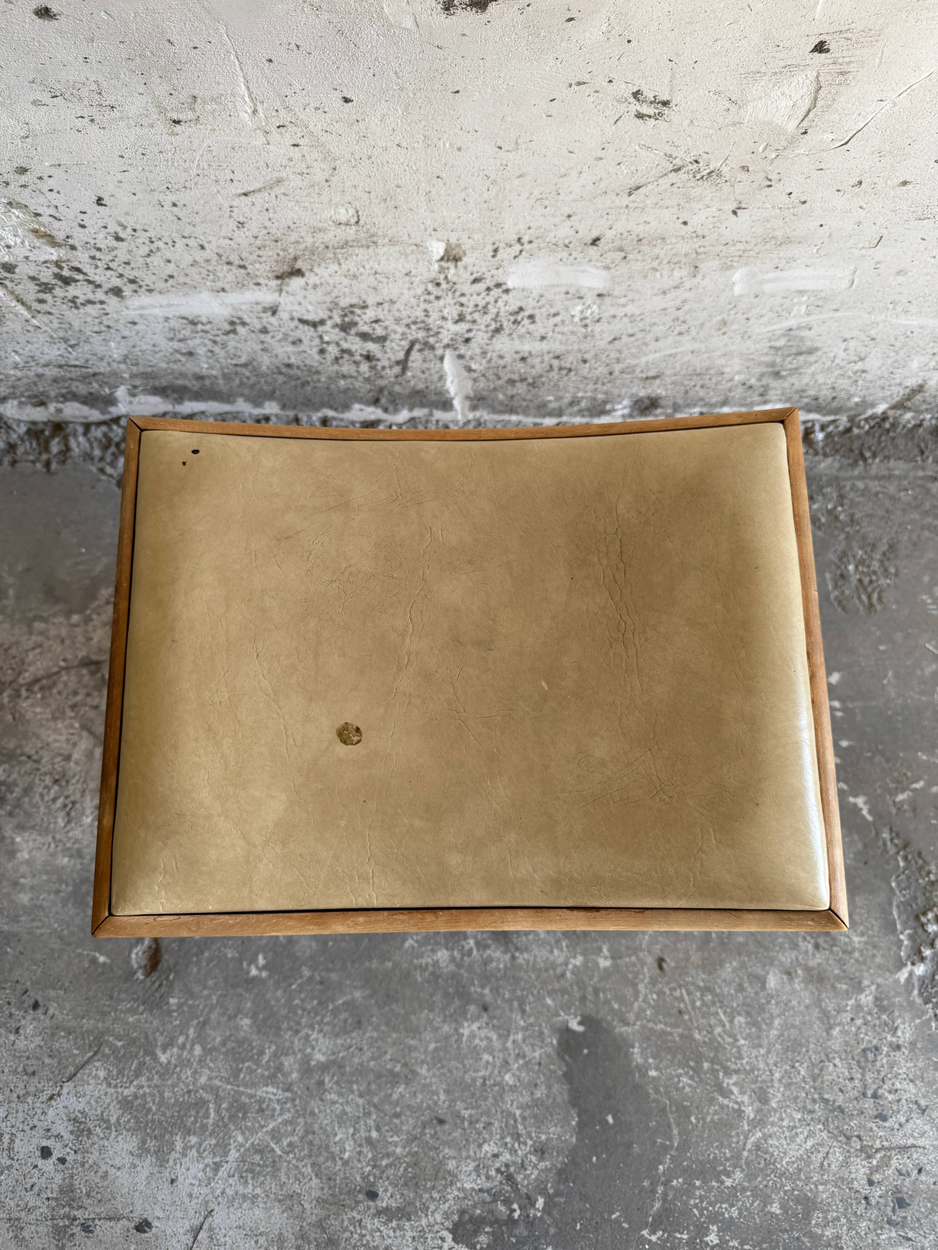 Vintage natural wood stool with light yellow faux leather seat and crossed splayed base