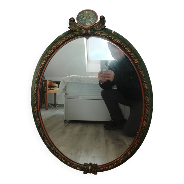 Miroir ovale ancien dans un cadre sculpté et peint avec un panneau floral