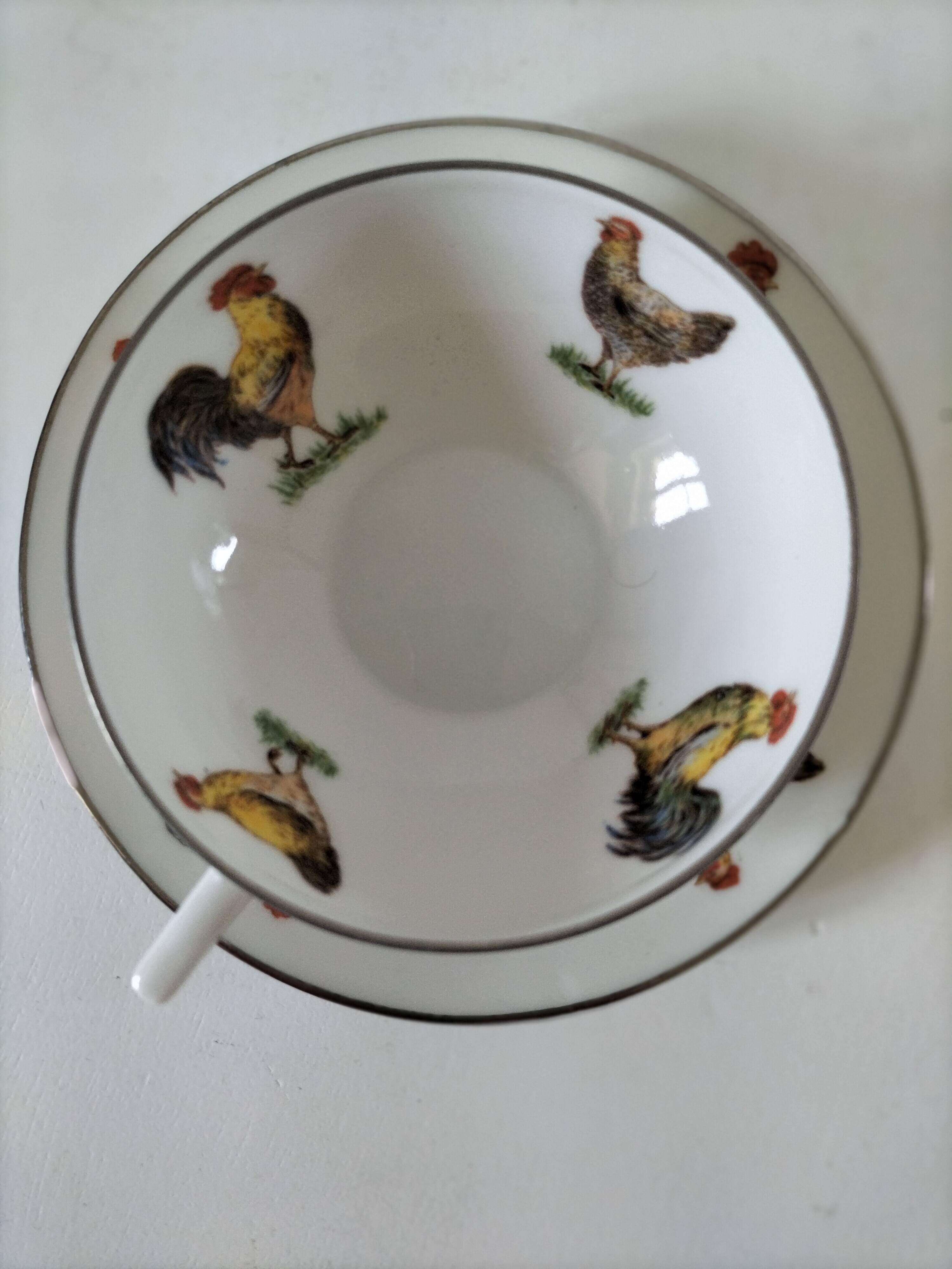 Cup and saucer in porcelain decorated with roosters and hens.
