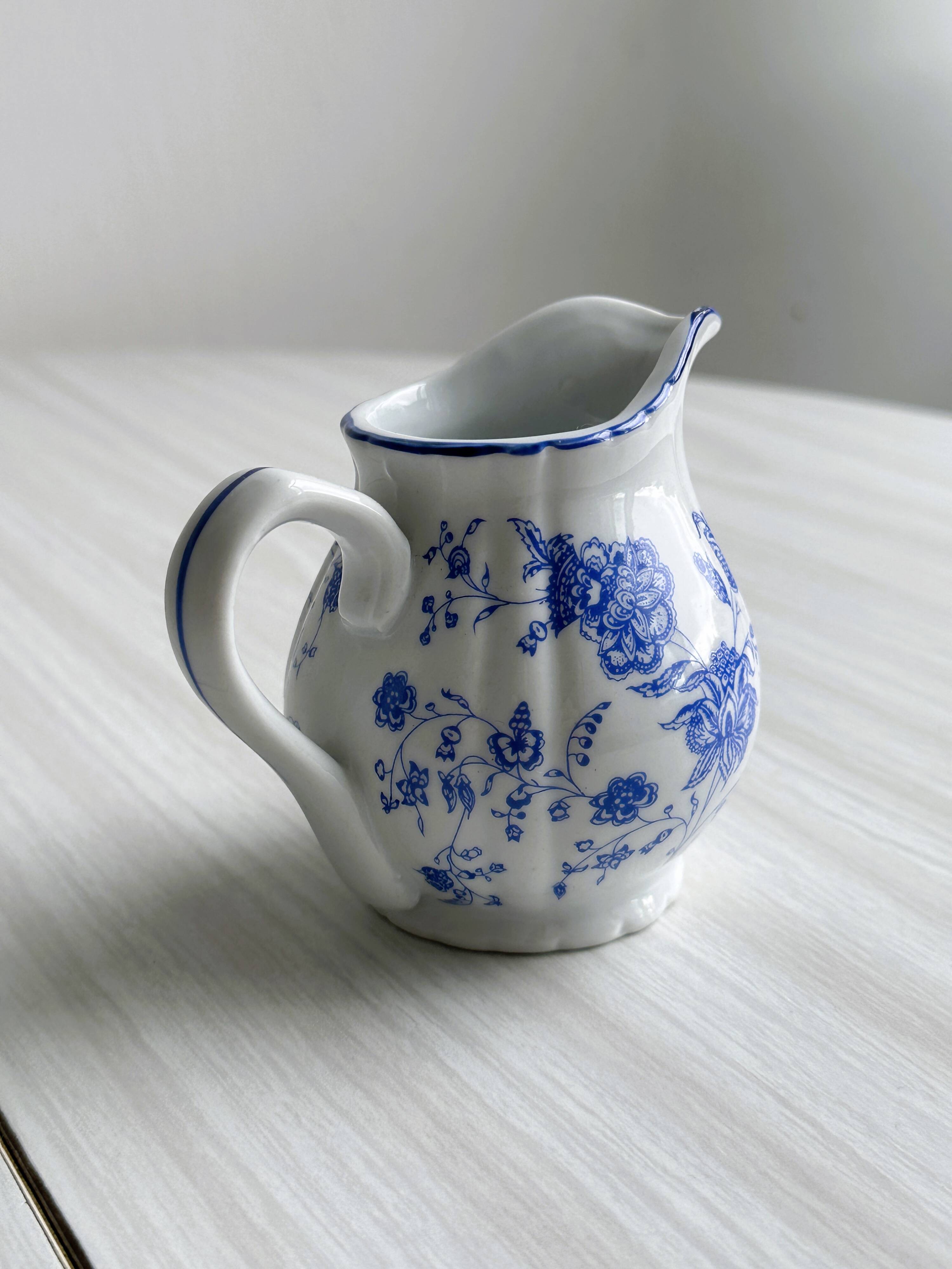 White porcelain milk jug with blue floral designs.