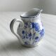 White porcelain milk jug with blue floral designs.