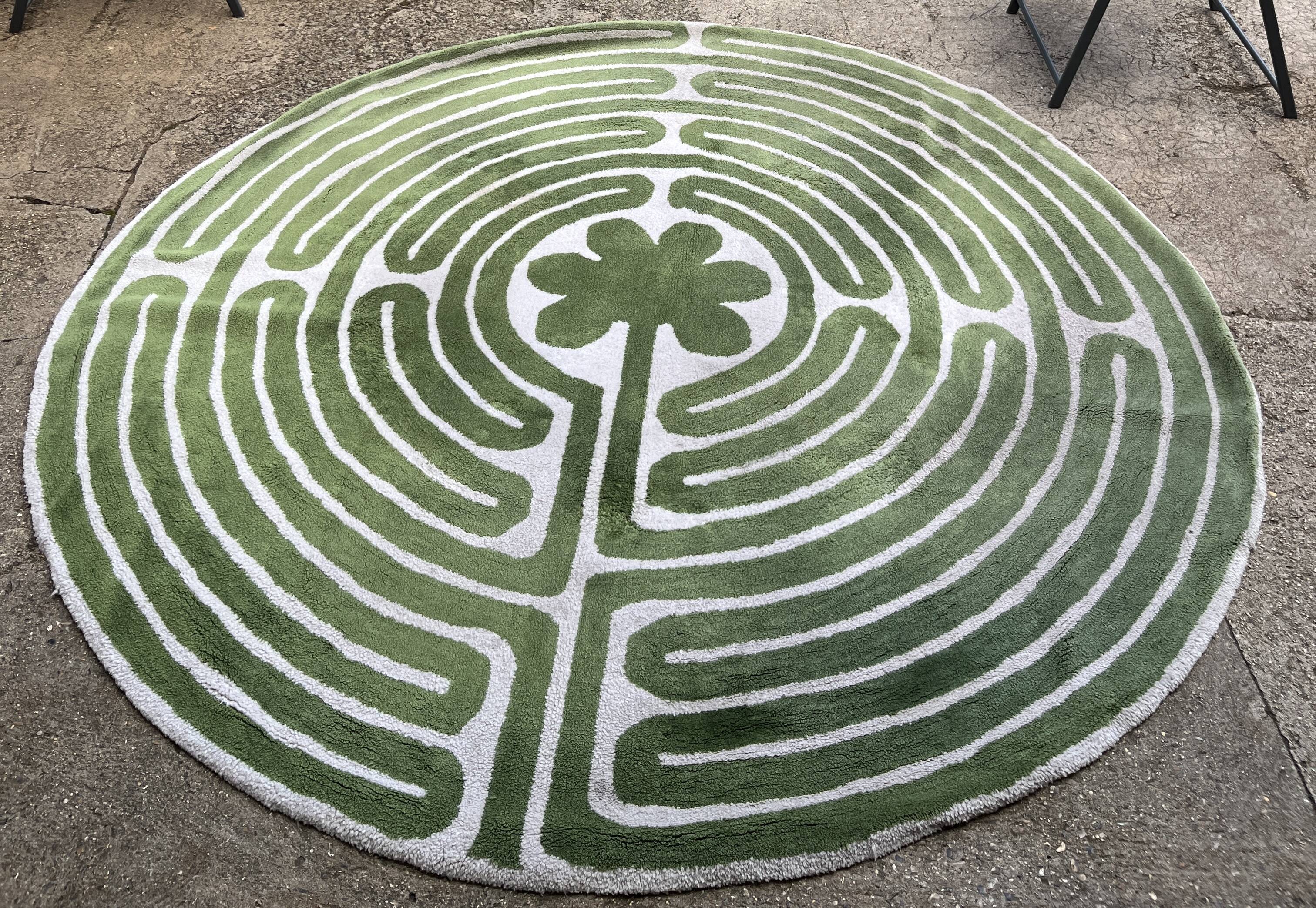 Circular rug with green decor on a cream background from the Labyrinth.