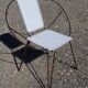 Black metal reclining armchair with white plastic caning.